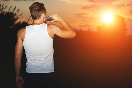 Runner drinking water of the bottle after intensive evening jog