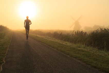 Man running in the foggy countryside near a windmill.
